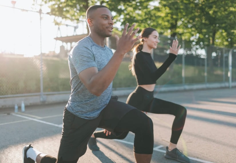 A man and a woman lunging side by side on a path outdoors
