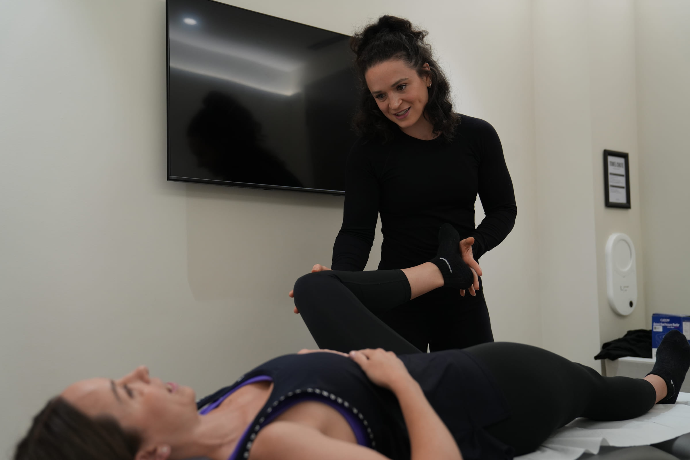 A coach assessing a client's hip range of movement on a treatment table