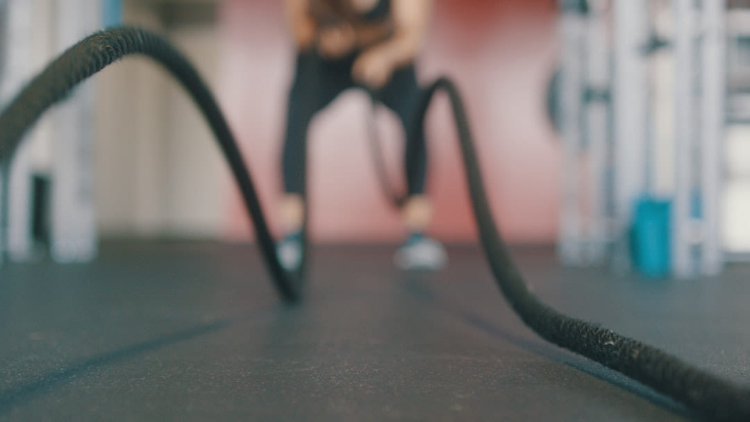 Battle ropes laid across a gym floor, a person out of focus behind them