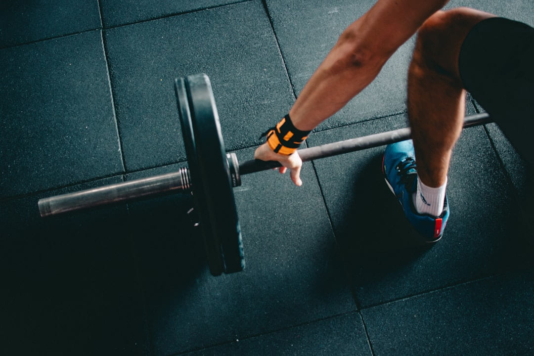 A lifter's hands and feet at the bottom of a deadlift beside a loaded barbell