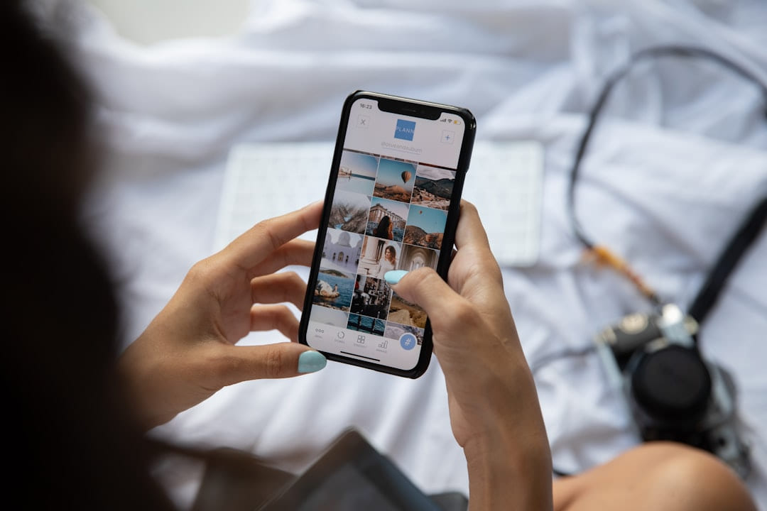 Hands scrolling a photo feed on a phone while lying in bed