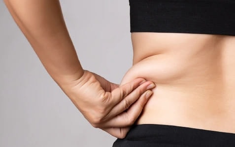 A person pinching the loose skin at their waist