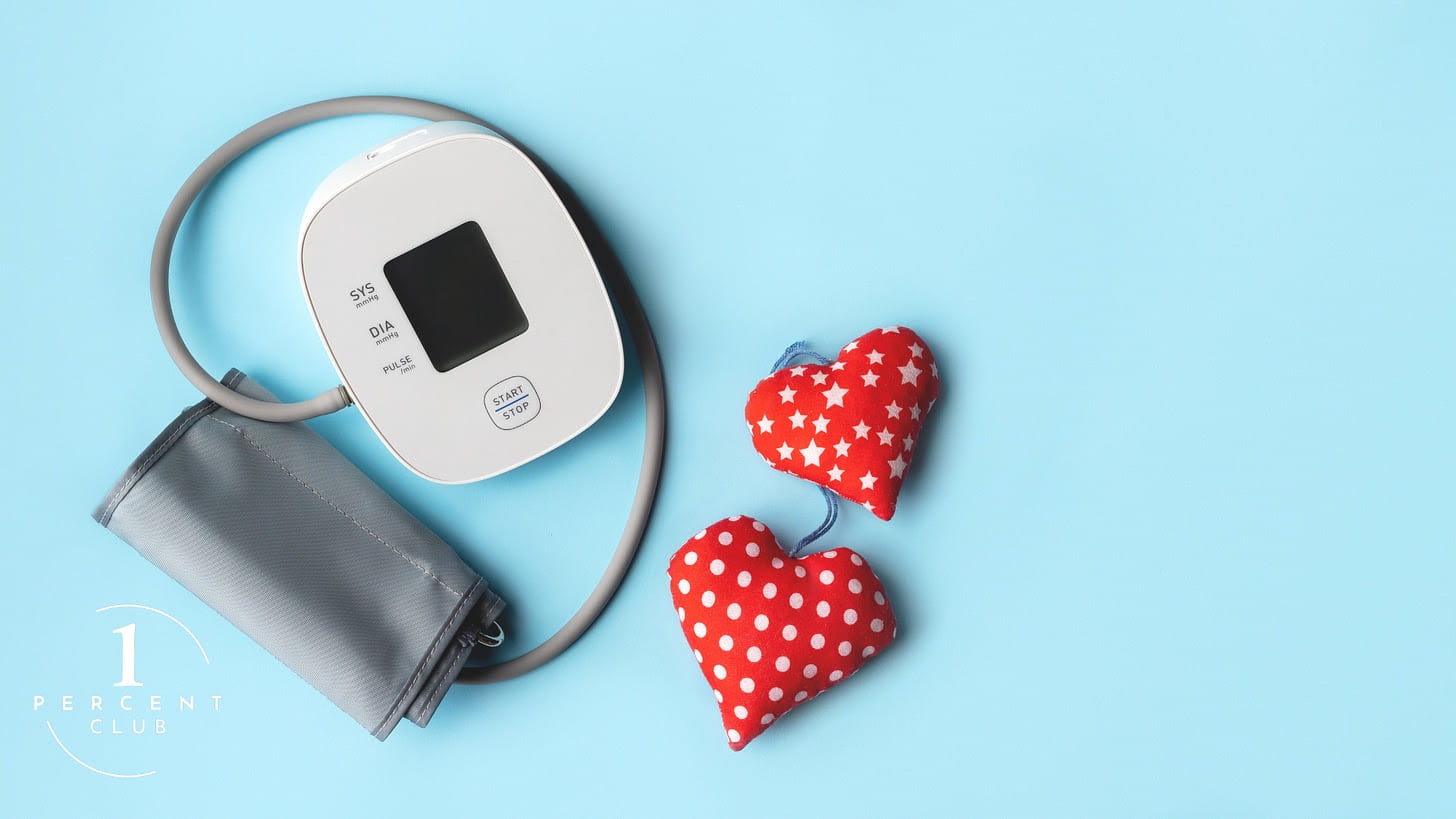 A home blood pressure monitor and two red fabric hearts on a pale blue background