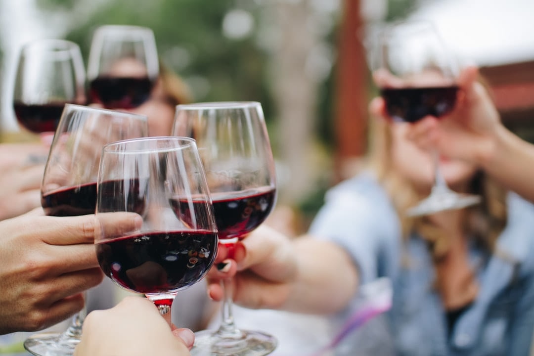 People touching glasses of red wine together outdoors