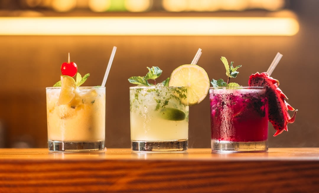 Three garnished cocktails lined up on a bar