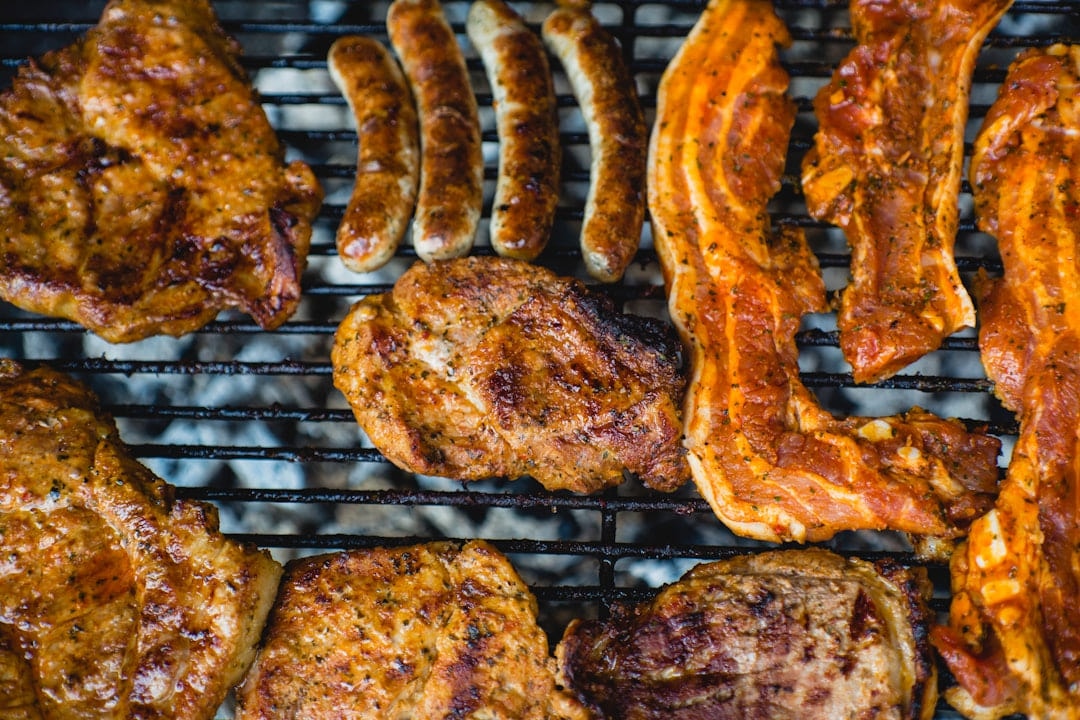 Sausages, bacon and chicken cooking on a barbecue grill