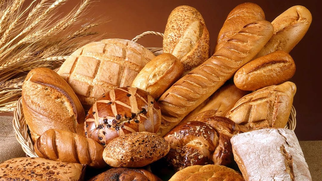 A basket of bread loaves and rolls with ears of wheat