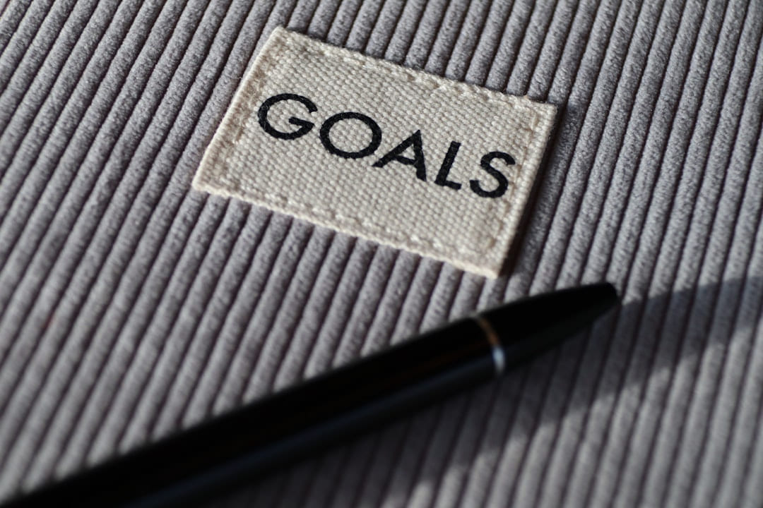A card printed with the word goals on grey fabric beside a pen