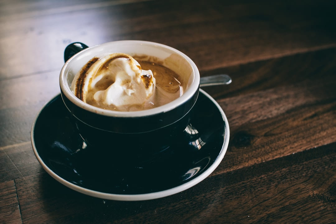 A coffee in a black cup and saucer on a wooden table