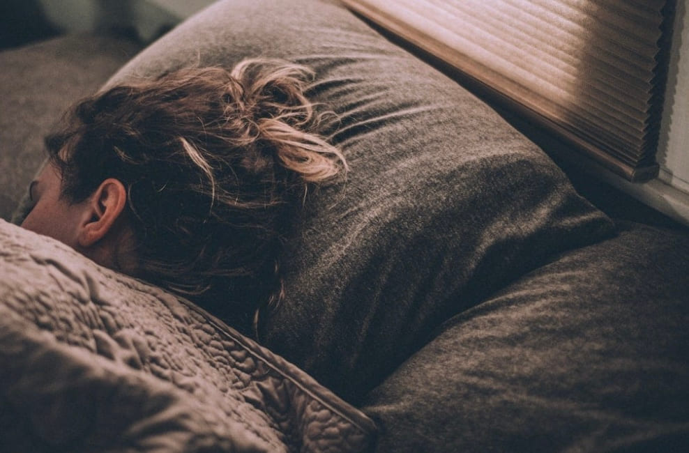 A person asleep in bed in low morning light