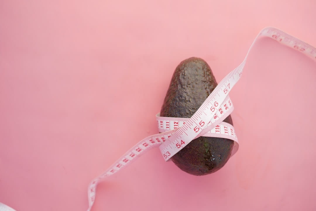 A smooth stone wrapped in a tape measure on a pink background