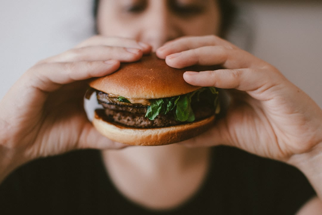 A person raising a burger to their mouth with both hands