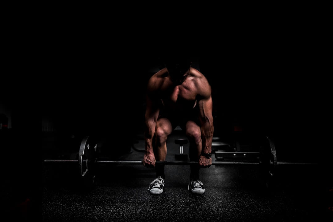 A lifter setting up over a barbell in a dark gym