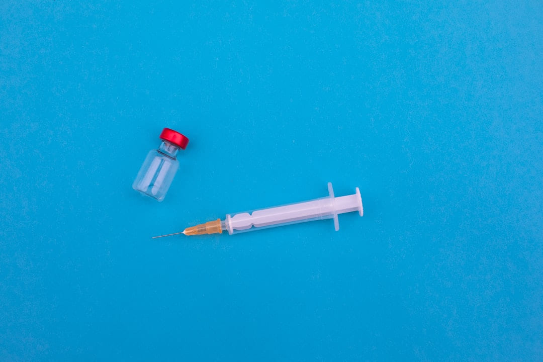 A small glass vial and a syringe on a blue background