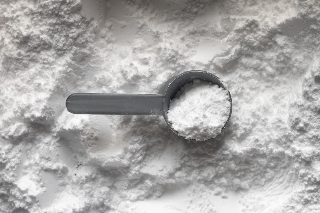 A scoop of white powder resting on a white surface