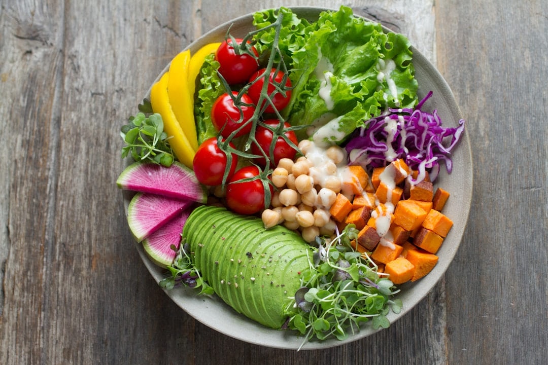 A salad bowl of avocado, chickpeas, sweet potato, radish and leaves
