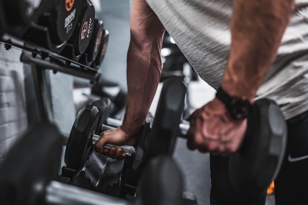 A man's hands lifting a pair of dumbbells from a rack