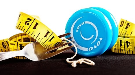 A blue yo-yo resting on a coiled tape measure