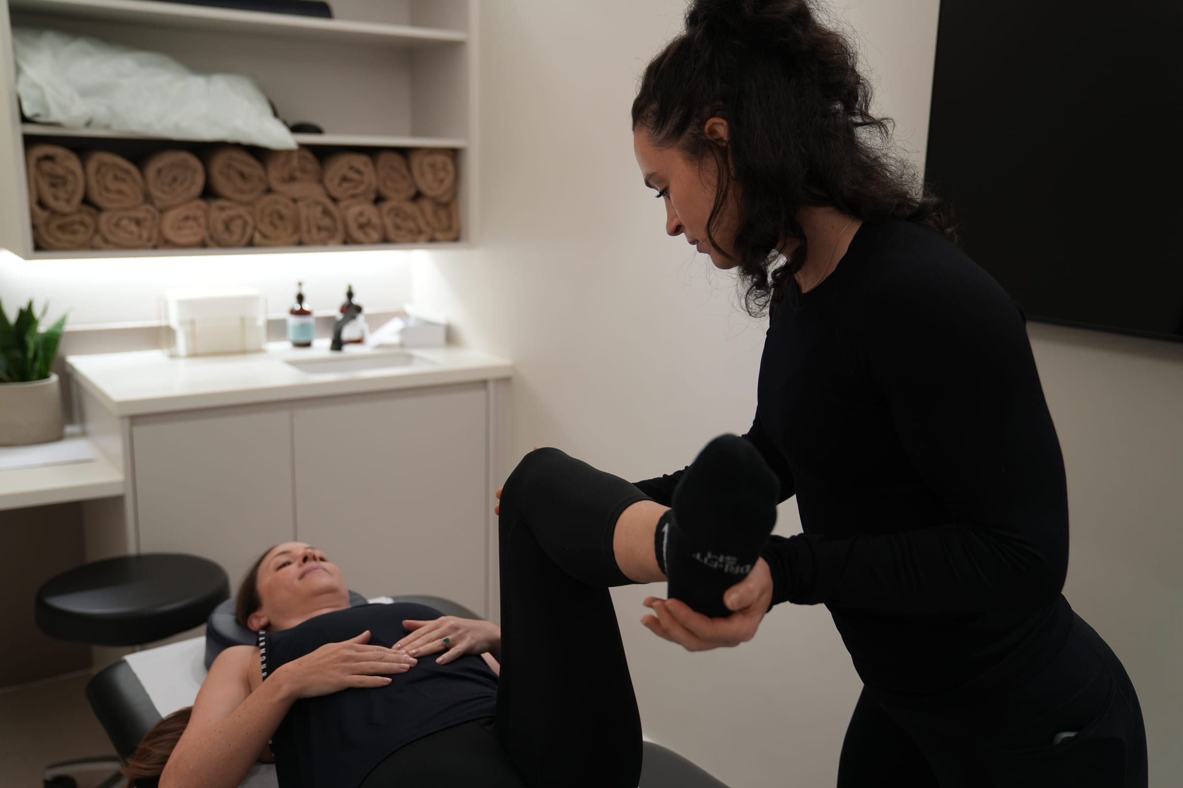 A therapist working on a client's leg on the treatment table