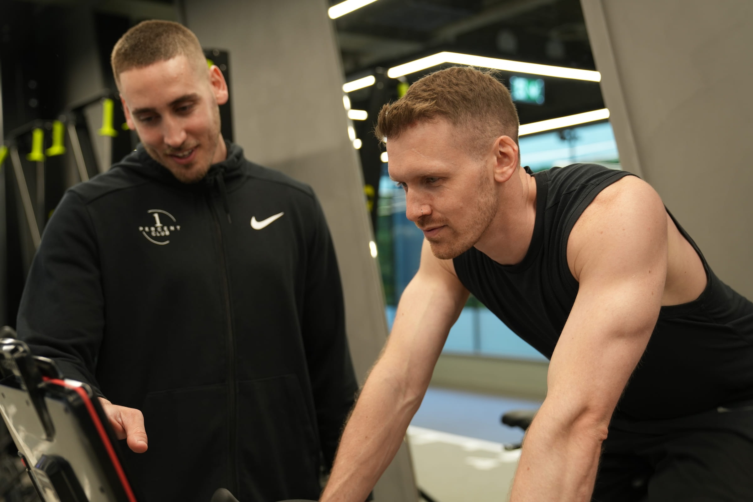 A coach and client talking between sets at the bikes