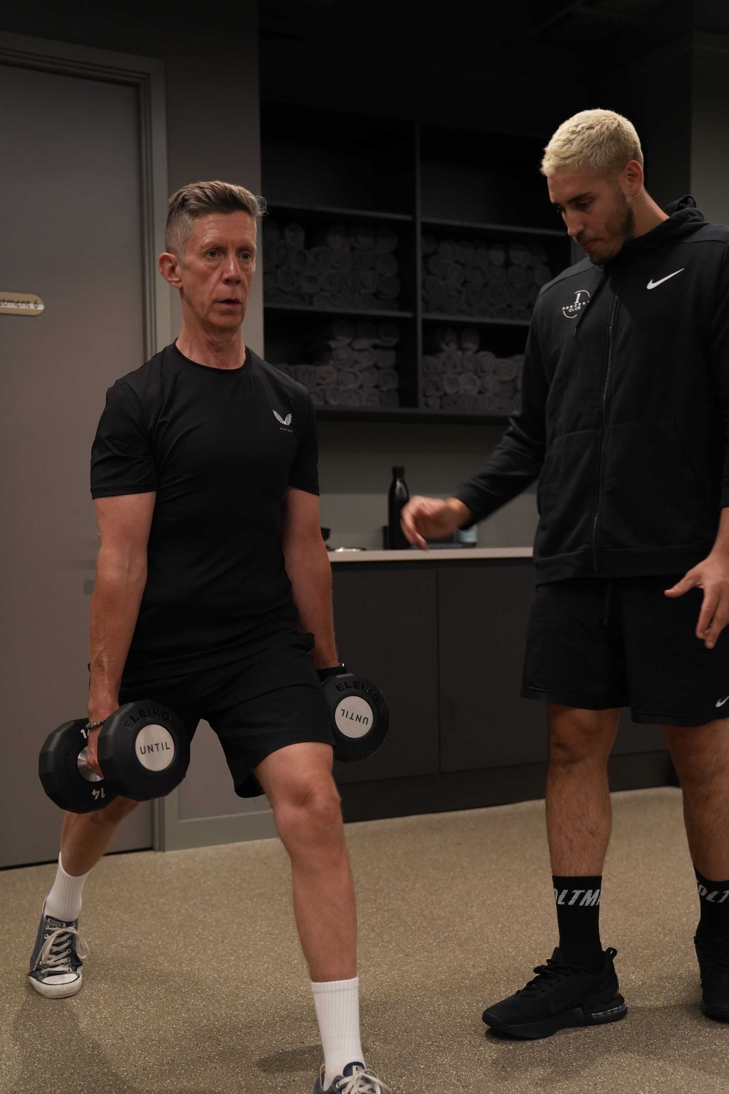 A coach talking a client through the next set, dumbbells in hand
