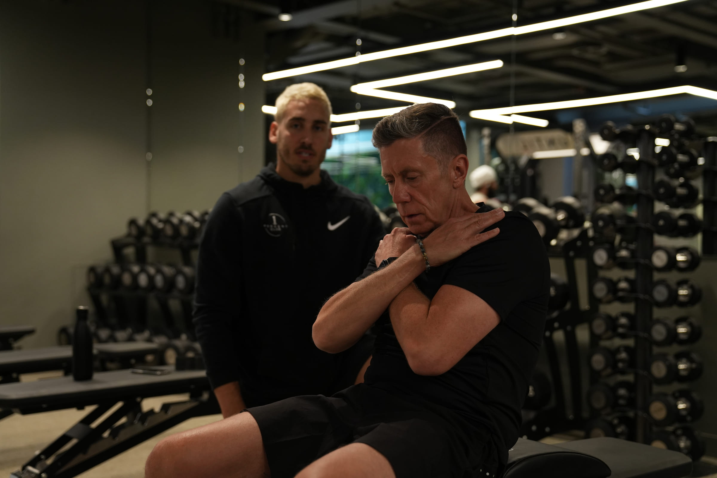 A coach talking a client through a core exercise on the training floor