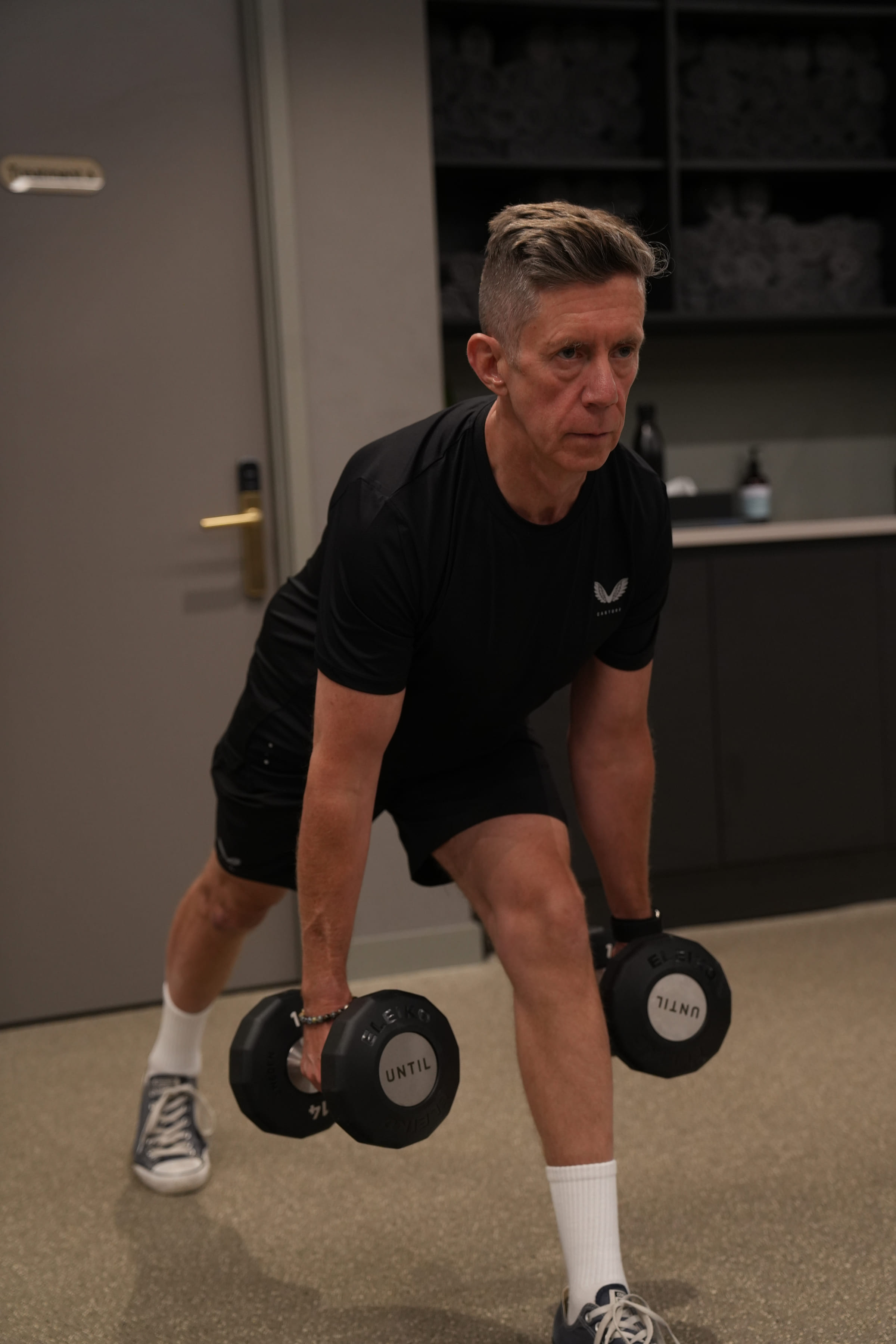 A coach watching a client's set-up through a dumbbell row