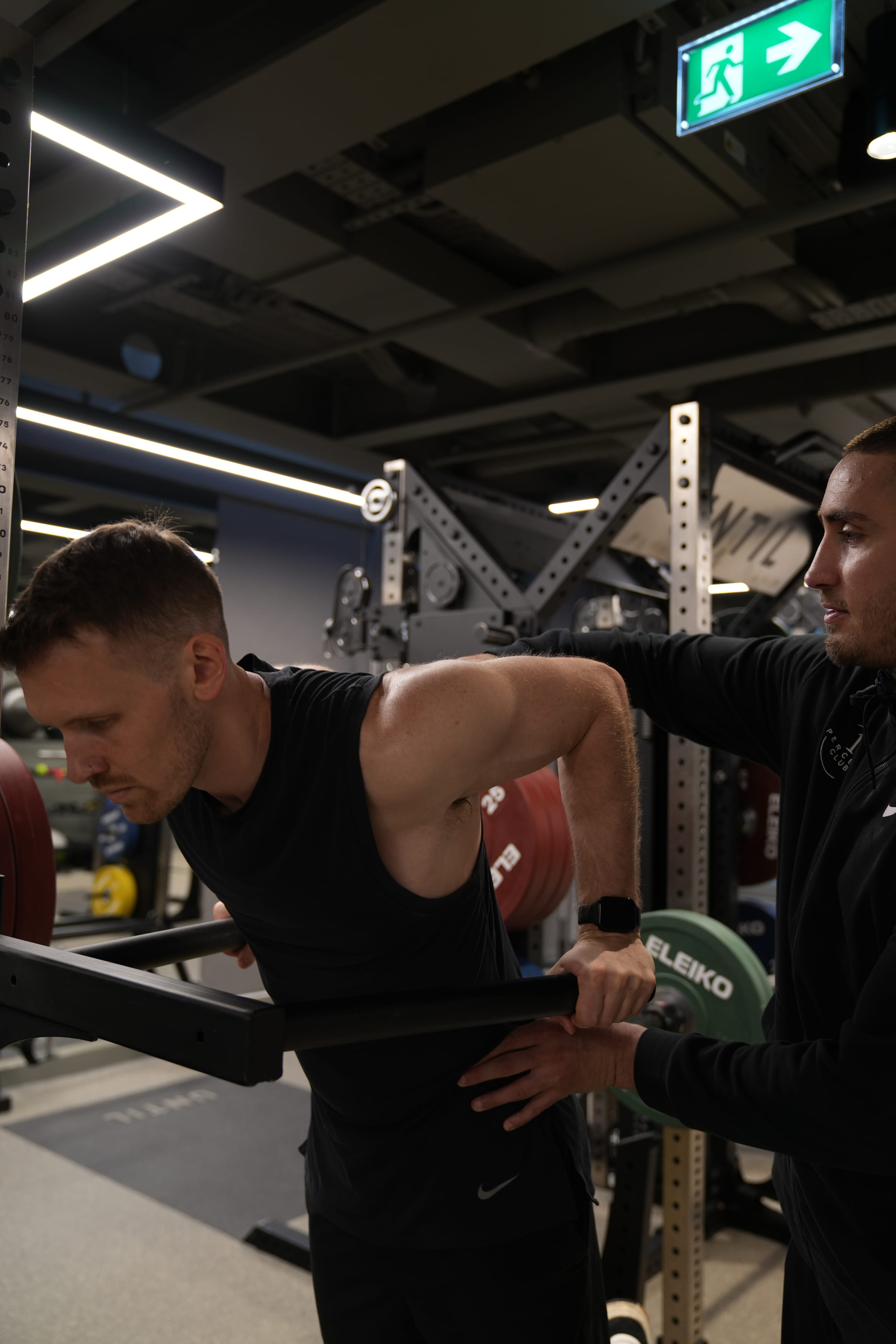 A coach cueing a client's row in the rack