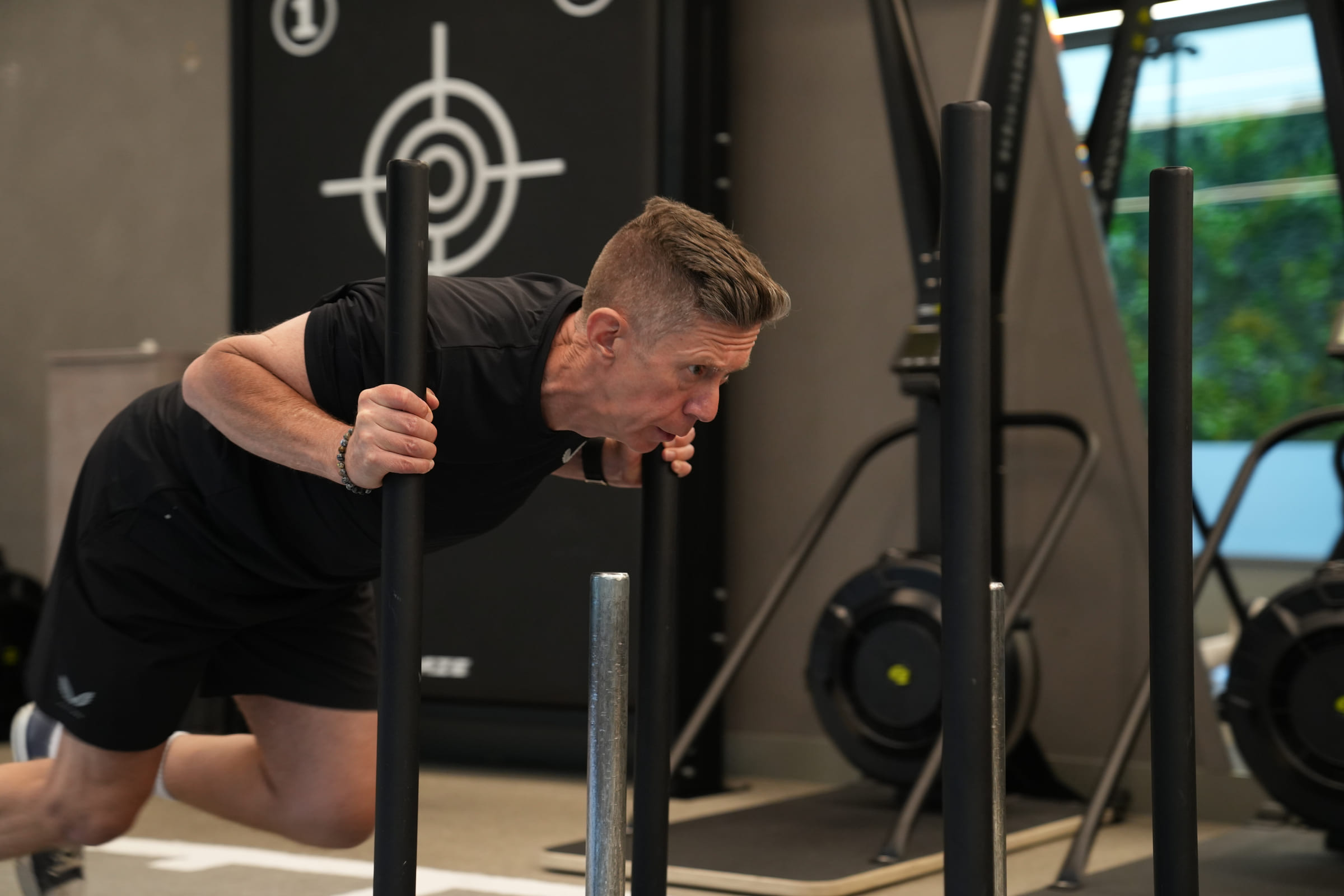 A client pushing a weighted sled with a coach alongside