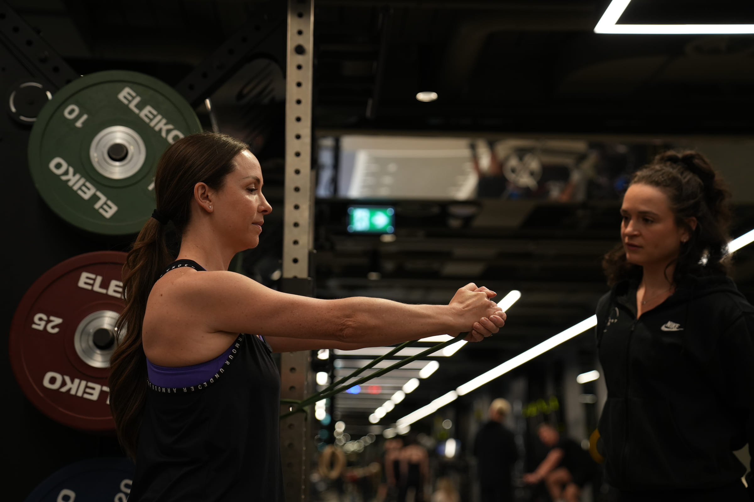 A client pressing out against a band with a coach checking her position